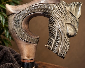 May include: A wooden walking cane handle carved into the shape of a wolf head with detailed fur texture. The handle features a smooth, light brown finish, while the shaft below includes a black and light wood section with a cross-hatch pattern.