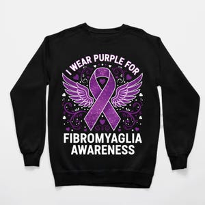 Puede incluir: Sudadera negra con un dise&ntilde;o de lazo morado, alas y el texto "I wear purple for Fibromyalgia Awareness". El dise&ntilde;o incluye corazones y adornos. Sudadera de cuello redondo.
