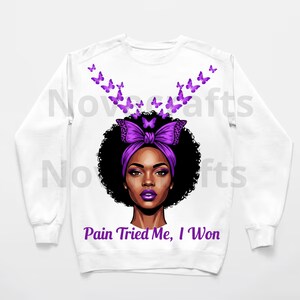 Puede incluir: Sudadera blanca con un gr&aacute;fico de una mujer con una diadema y un lazo morados, rodeada de mariposas moradas. El texto "Pain Tried Me, I Won" est&aacute; impreso debajo de la imagen. El dise&ntilde;o est&aacute; centrado en la parte delantera de la parte superior de manga larga.