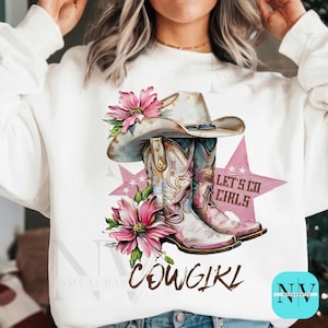 Peut inclure: Sweat-shirt blanc avec un motif graphique d'un chapeau de cow-boy, de bottes et de fleurs roses. Le motif comprend les mots "Cowgirl" et "Let's Go Girls" sur un fond d'étoile rose.
