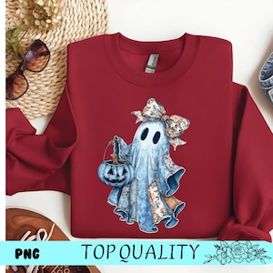 Peut inclure: Un sweat-shirt ras du cou bordeaux avec un motif de fantôme à l'aquarelle tenant une lanterne citrouille. Le fantôme a un nœud floral et des détails de patchwork. Le texte "TOP QUALITY" est en bas.