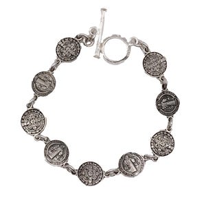 May include: A silver-toned bracelet featuring circular medallions with religious iconography. The bracelet has a toggle clasp and is composed of interconnected links. The medallions display detailed engravings and are evenly spaced along the chain.