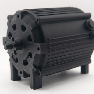 Könnte beinhalten: Schwarze mechanische Komponente mit zylindrischem Körper und zahnradartigem Ende. Die Komponente hat eine Reihe paralleler Rippen an der Seite und wird von vier kleinen Beinen getragen. Das Design deutet auf einen Motor oder ein ähnliches mechanisches Gerät hin.