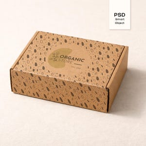 Op de afbeelding: Een rechthoekige kartonnen doos met een bruin gespikkeld patroon en de woorden "ORGANIC STORE" op de bovenkant. De doos is gesloten en staat op een wit oppervlak. De doos heeft ook de woorden "PSD Smart Object" op een witte kaart.