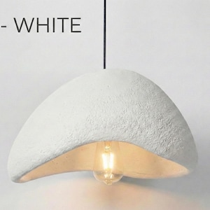 May include: White, textured pendant light fixture with a unique, organic shape. The light has a bulb visible at the bottom and is suspended from a black cord. The text "A - WHITE" is above the light.