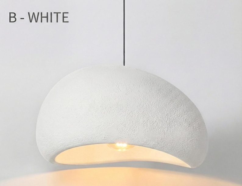 May include: White, textured, pendant light fixture with a curved, organic shape. The light fixture is suspended from a black cord and has the text "B - WHITE" in the upper left corner.