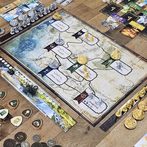 Peut inclure: Jeu de société avec un plateau de jeu cartographique, des figurines miniatures, des cartes et des jetons. Le plateau de jeu présente une rose des vents et des zones étiquetées. Divers éléments de jeu sont disposés sur une surface en bois, prêts à jouer.