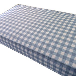 A plump, custom made indoor bench cushion with green gingham cotton and linne upholstery fabric cover. A foam and dacron wadding seat cushion for a dining room bench seat with piping cord at the edges. The bench cushion cover has a blue and off white check pattern in a hard wearing fabric. Stain resistant cover for a storage bench cushion with a zip at the back for cleaning. Made to measure upholstery foam cushion for a wooden seating bench. Window seat cushion in gingham pattern fabric.