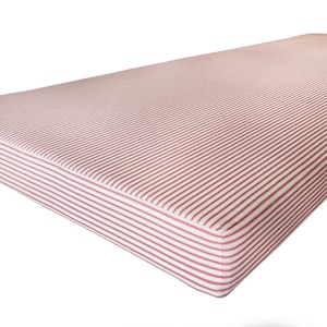 A large, thick day bed cushion made with firm upholstery foam inside. The cushion is 10cm thick and is supportive and comfortable to sit on. The bench cushion has a cover with a zip at the back. The cover is made with a red and white french style ticking stripe fabric which is 100% cotton. The bench cushion is plain with no piping giving a sleek, contemporary aesthetic. The cushion can have an additional stain resistant treatment making it perfect for use around children or kids in dining spaces