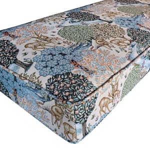 May include: A rectangular bench cushion with a detailed tapestry design. The fabric features a forest scene with trees, deer, and other wildlife in shades of blue, green, and brown against a cream background. The cushion has a thick, padded appearance.