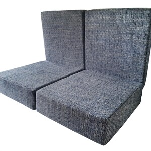 May include: Two upholstered chairs with a high back and a square seat. The chairs are covered in a textured, blue-gray fabric. The chairs are placed side by side.