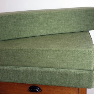 A set of cushions for a campervan conversion in a thick, durable fire retardant green fabric. Wipe clean sleeping cushions for camper van renovation. Made to measure in the UK by a smally family business. Locally sourced materials. Stowaway bed cushions, sprinter bed system cushions. Firm upholstery foam inners with memoryy foam toppers and velcro strips to keep cushions in place. Durable performance fabrics for long lasting camper van cushions. Made to measure, any shape or size, thickness