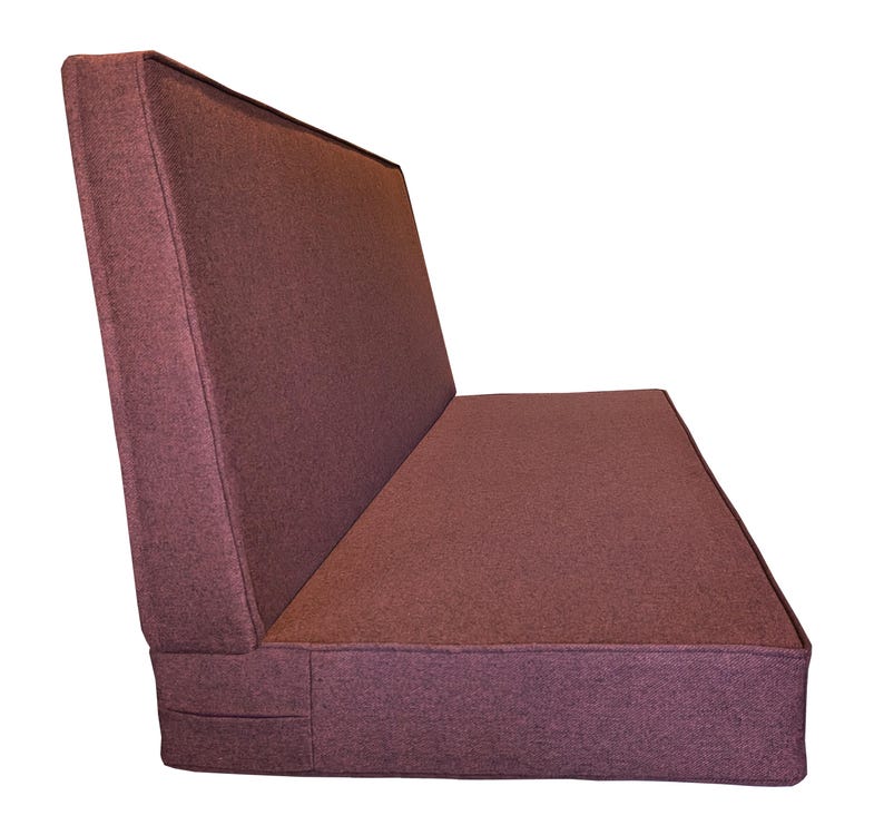 May include: A burgundy-colored, upholstered bench with a backrest. The bench has a rectangular seat and back, with a slightly angled backrest. The fabric appears to be a textured weave.