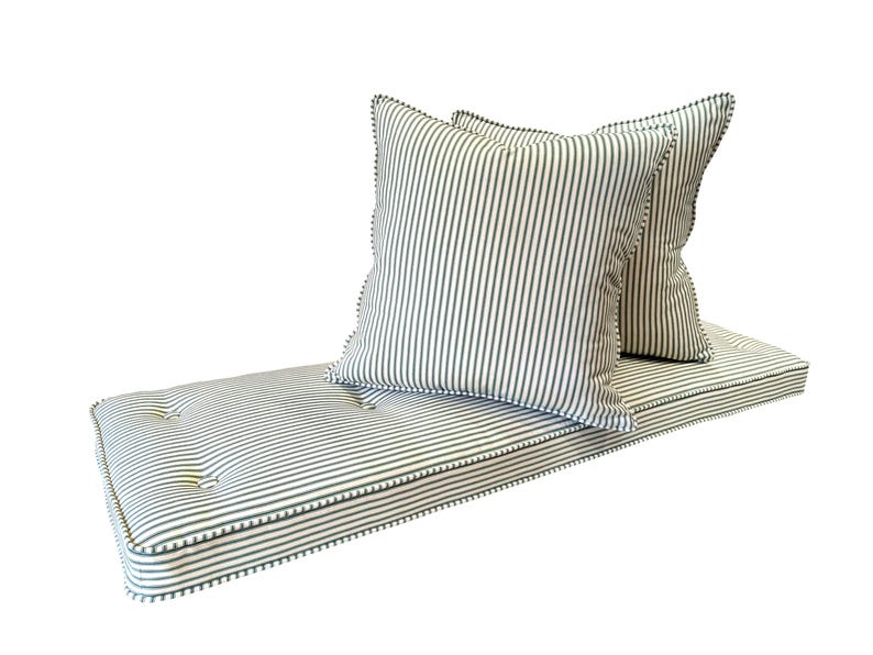 A firm upholstery foam bench cushion made to measure to custom size. The bench cushion cover is made to order in a 100% cotton, natural fabric striped ticking fabric made in the UK. The green and white stripey fabric bench cushion is button tufted with firm foam and dacron inside. The zip at the back of the cushion allows the covers to be removed. Two scatter cushions with eco fibre filling in the same off white and racing green stripe fabric. French chic ticking fabric bench cushion