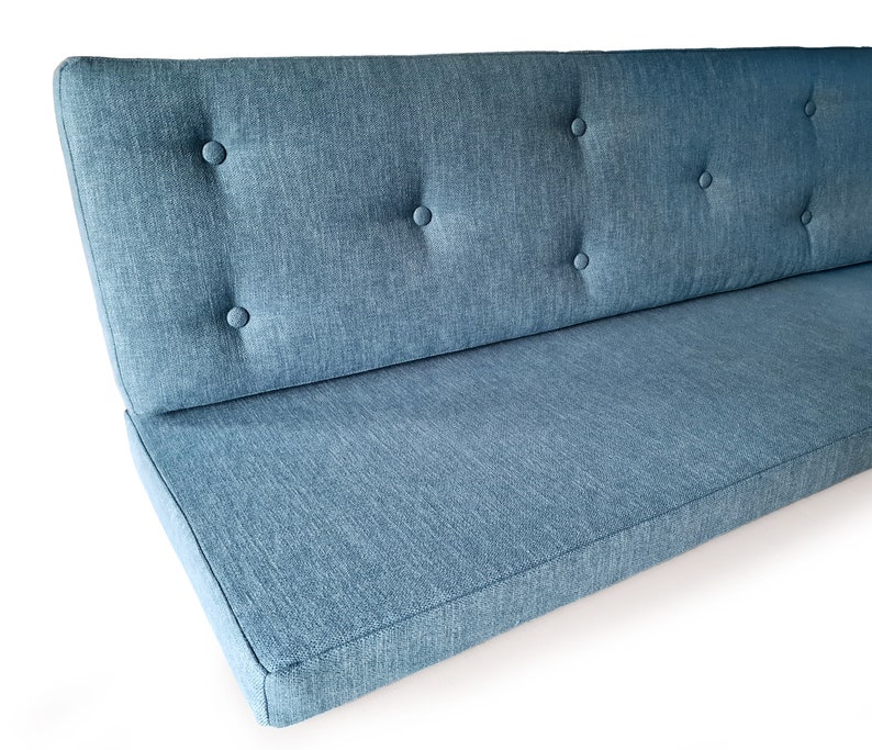 A set of two cushions for a dining seat area. There is a seat cushion which is made with firm upholstery foam which is long lasting and comfortable. The back cushion in the set is made with the same foam, with a dacron layer. The back cushion has been hand tufted with buttons in the same blue fabric. The back and seat cushions both have covers made with a mid blue, woven, linen look fabric which is hard wearing and stain resistant. The seat cushion for the banquette has a zip at the back