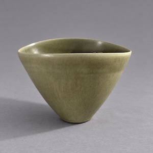 Pode incluir: Uma tigela de cerâmica com formato cônico afunilado e acabamento fosco liso em um tom verde-oliva suave. A borda da tigela é levemente irregular, formando uma silhueta triangular suave que se estreita em direção a uma base circular pequena.