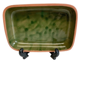 May include: A rectangular green glazed ceramic baking dish with a terracotta rim. The dish is on a white background.