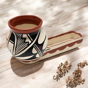 May include: A handcrafted ceramic pottery piece with a round bowl and an attached rectangular tray. The bowl features a black and white geometric design with a reddish-brown rim. The tray has a scalloped edge and a reddish-brown border.