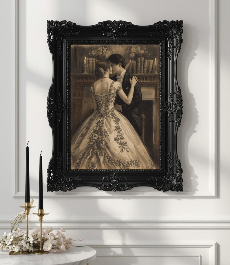 May include: A sepia-toned framed print depicts a couple in formal attire embracing. The woman wears a detailed gown, and the man is in a suit. The black ornate frame complements the romantic scene. Two black candles in gold holders and flowers are in the foreground.