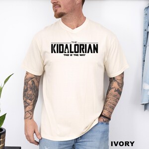 A man wearing a white t-shirt with the text "THE KIDALORIAN THIS IS THE WAY" printed on it.