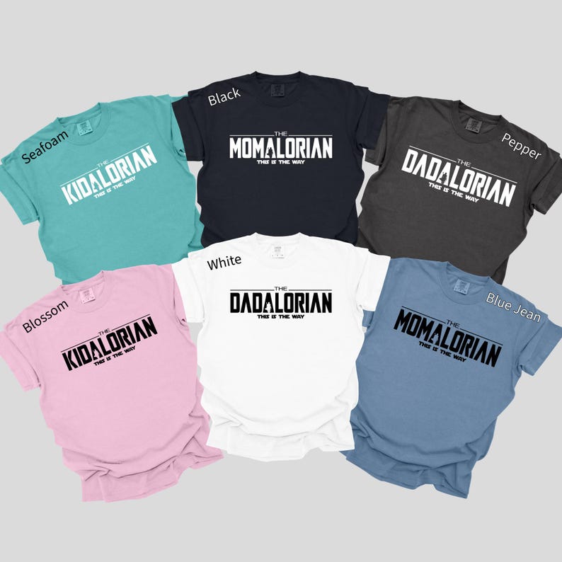 a collection of seven T-shirts, each with a different color and design, featuring the text "The Dadalorian" printed on them.