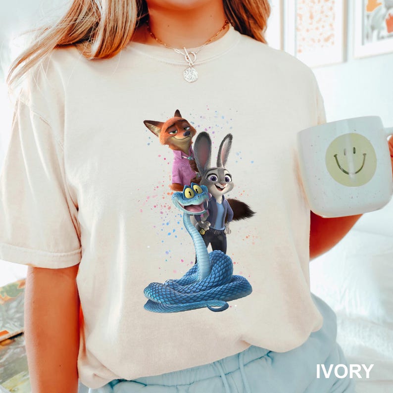 A person wearing a white t-shirt with a graphic of three cartoon animals - a fox, a rabbit, and a snake - standing together.