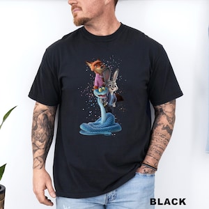 A man wearing a black t-shirt with a graphic of a fox, rabbit, and snake on it.