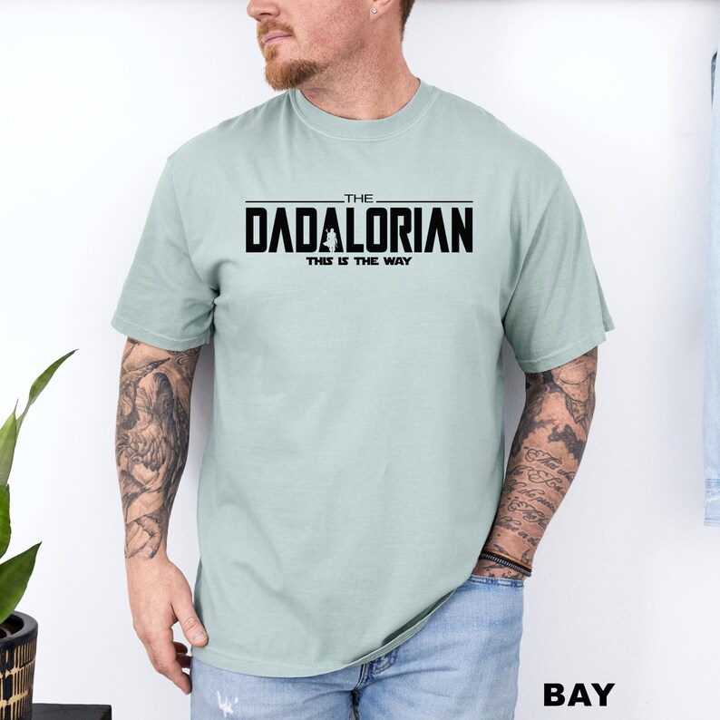 A man wearing a light green t-shirt with the text "The DADALORIAN THIS IS THE WAY" printed on it.