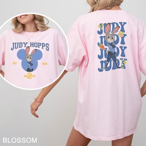 A woman wearing a pink t-shirt with a cartoon image of Judy Hopps, a character from the Disney movie "Zoografia".