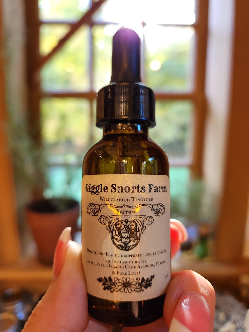 May include: A brown glass bottle with a dropper top and a label that reads "Giggle Snorts Farm Wildcrafted Tincture Yarrow". The label also includes directions for use and a list of ingredients, including organic cane alcohol, yarrow, and pure love.