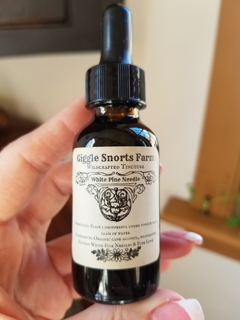 K&ouml;nnte beinhalten: Eine Glasflasche mit Tropfer, die eine dunkle Fl&uuml;ssigkeit enth&auml;lt. Das Etikett lautet "Giggle Snorts Farm Wildcrafted Tincture White Pine Needle". Das Etikett enth&auml;lt auch Gebrauchsanweisungen und Zutaten, darunter Bio-Rohrzuckeralkohol, wildgewachsene Wei&szlig;kiefernnadeln und reine Liebe.