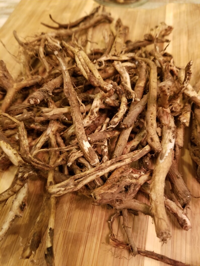 May include: A pile of dried, brown roots on a wooden chopping board. The roots are long and thin, with a rough texture.