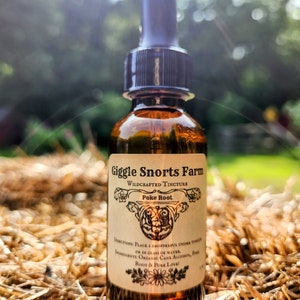 May include: A brown glass bottle with a dropper top, labeled "Giggle Snorts Farm Wildcrafted Tincture Poke Root". The bottle is sitting on a bed of straw.