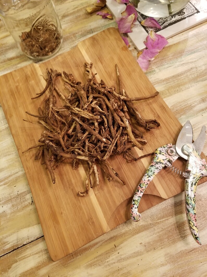 May include: A pile of dried brown roots on a wooden chopping board with a floral patterned pruning shears.