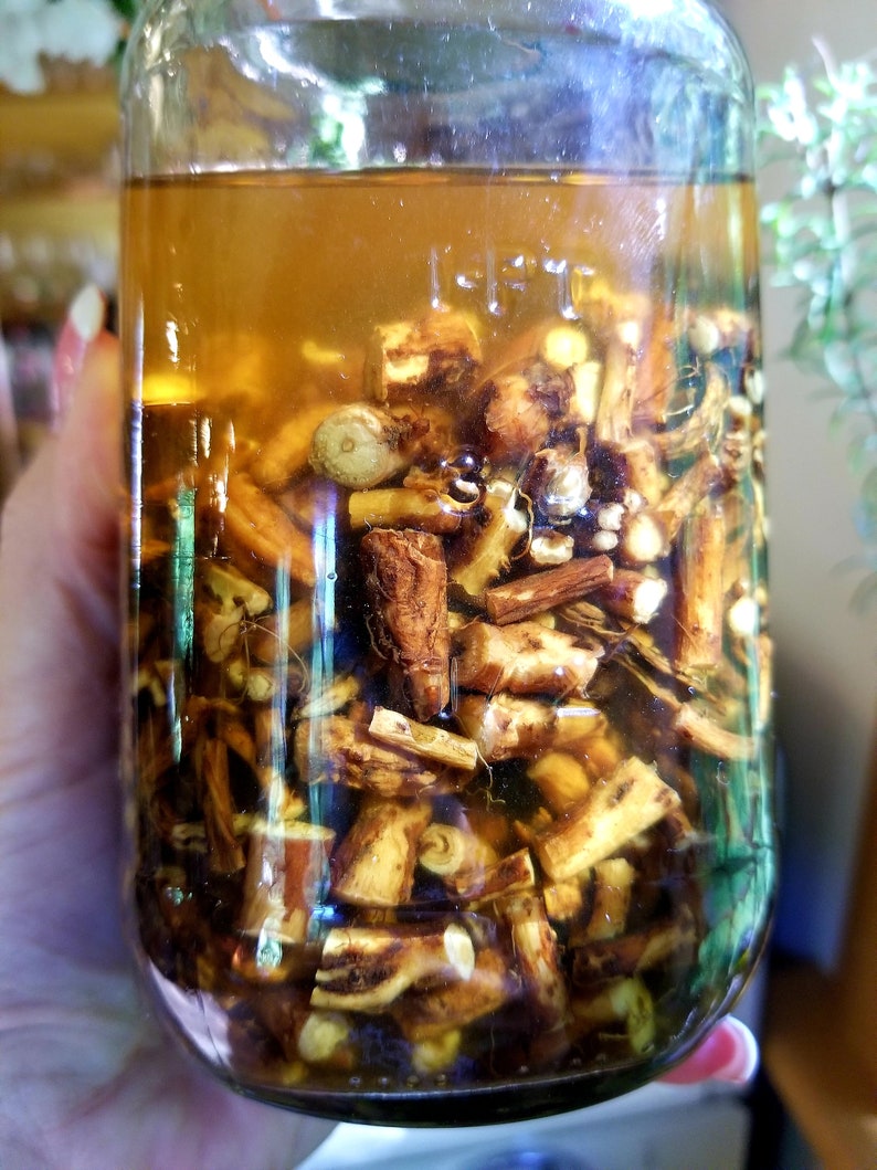 May include: A glass jar filled with a clear liquid and brown, dried roots. The jar is partially filled with the liquid and the roots are visible through the glass.