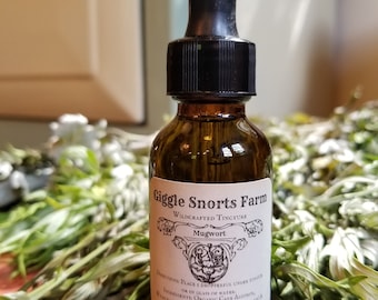 Puede incluir: Una botella de vidrio marrón con un gotero negro y una etiqueta blanca que dice "Giggle Snorts Farm Wildcrafted Tincture Mugwort Directions: Place 1 dropperful under tongue or in glass of water. Ingredients: Organic Cane Alcohol, Wildcrafted Mugwort(Artemisia Vulgaris) Pure Love!"