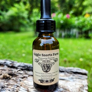 May include: A small brown glass bottle with a black dropper top. The bottle is labeled "Giggle Snorts Farm Wildcrafted Tincture Poke Root". The label also includes directions for use and ingredients: "Place 1 dropperful under tongue or in glass of water. Ingredients: Organic Cane Alcohol, Poke Root & Pure Love!"