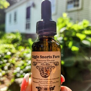 May include: A brown glass bottle with a dropper top and a label that reads "Giggle Snorts Farm Wildcrafted Tincture Poke Root". The label also includes directions for use and ingredients, which are "Place 1 dropperful under tongue or in glass of water. Ingredients: Organic Cane Alcohol, Poke Root & Pure Love!"