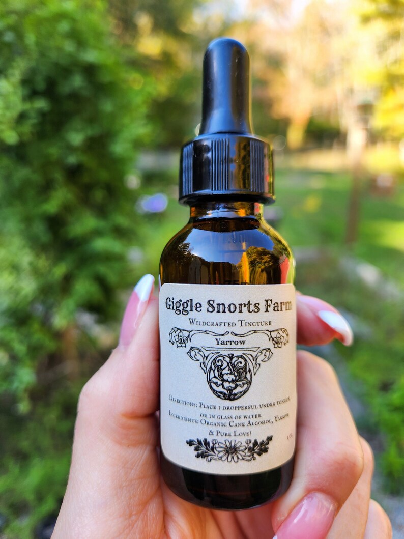 May include: A brown glass bottle with a black dropper top. The label reads "Giggle Snorts Farm", "Wildcrafted Tincture", "Yarrow", "Directions: Place 1 dropperful under tongue or in glass of water", "Ingredients: Organic Cane Alcohol, Yarrow & Pure Love!"