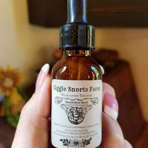 May include: A glass bottle with a dropper top and a white label that reads "Giggle Snorts Farm Wildcrafted Tincture Dandelion Root". The label also includes instructions for use and a list of ingredients.