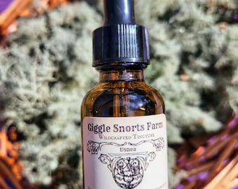 May include: A glass bottle with a dropper filled with a clear liquid. The bottle has a label that reads "Giggle Snorts Farm Wildcrafted Tincture Usnea". The label also includes directions for use and ingredients, which include organic cane alcohol, wildcrafted usnea, and pure love.