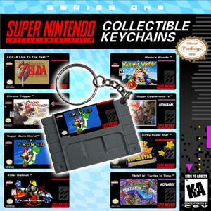 Puede incluir: Una exhibición de llaveros coleccionables de Super Nintendo. La imagen presenta un llavero gris de Super Mario World, con otros llaveros de cartuchos de juegos en el fondo. El texto "Super Nintendo Entertainment System" está en la parte superior.