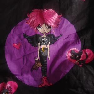 May include: A whimsical illustration of a gothic-style angel girl with pink glitter hair, black wings, and a skull and crossbones on her shirt. She holds a teddy bear and is surrounded by hearts and spiders on a black background.