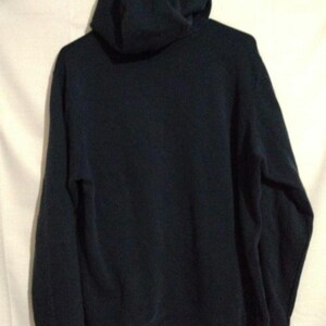 May include: A dark navy blue hooded sweatshirt. The sweatshirt features a hood and long sleeves. The garment is made of a soft material. The back of the sweatshirt is visible.