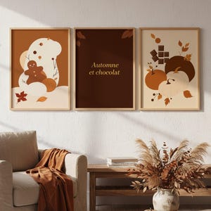 May include: Three framed art prints with autumnal illustrations. One shows a gingerbread man, another reads "Automne et chocolat," and the third depicts pumpkins and chocolate squares. The colour palette includes warm browns, oranges, and creams.