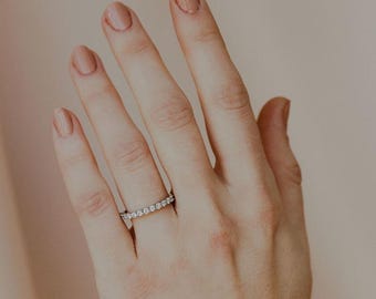 Op de afbeelding: Een delicate zilveren ring met een doorlopende rij kleine, heldere edelstenen. De ring wordt gedragen aan een hand met gepolijste nagels, tegen een zachte, neutrale achtergrond. Het ontwerp van de ring is eenvoudig en elegant, geschikt voor dagelijks gebruik.