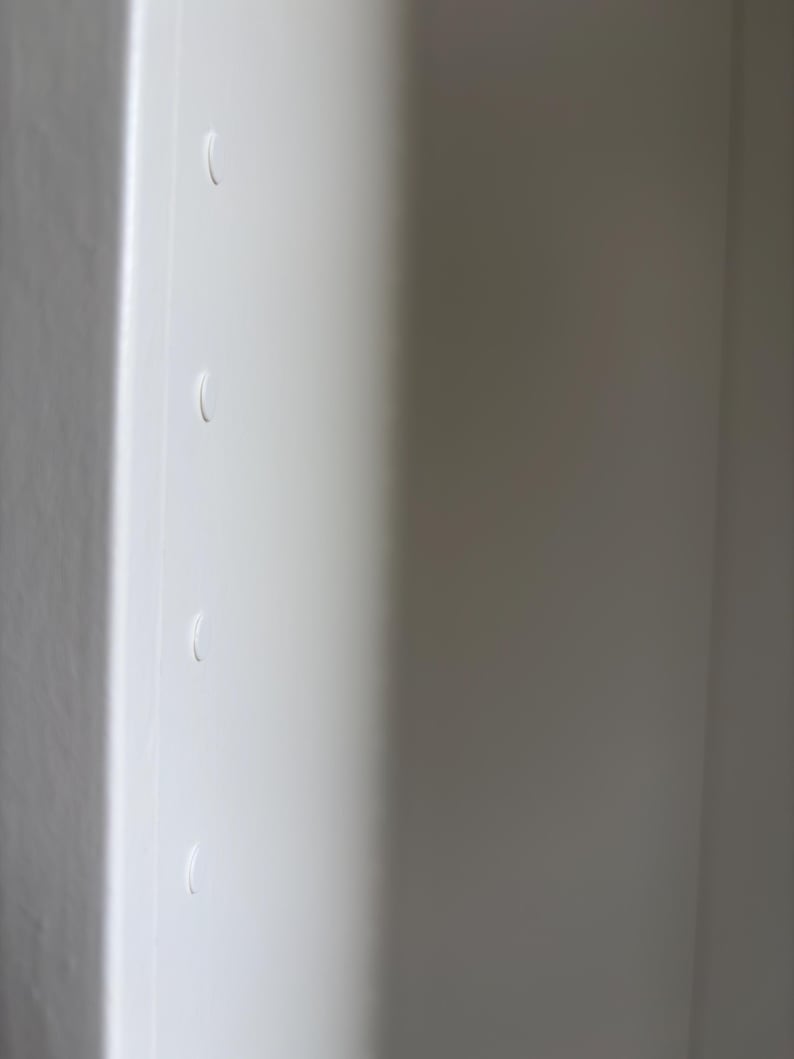 May include: A close-up of a white, smooth surface with four curved indentations. The surface is divided by a vertical line, with the right side in shadow. The indentations are evenly spaced.