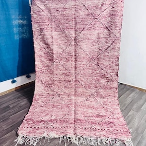 May include: A rectangular area rug featuring a deep magenta and white mottled color palette. The rug displays a repeating diamond pattern formed by dark lines across the surface, finished with a white knotted fringe along the bottom edge.