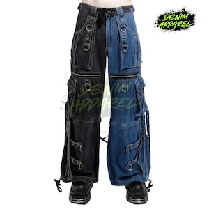 May include: Two-tone denim pants, black on the left and blue on the right, with multiple pockets, zippers, and metal ring accents. The pants have a drawstring waist and are branded with "DENIM APPAREL" in a green splatter design.