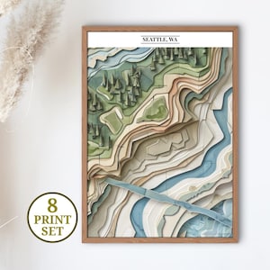 May include: A framed topographical map print of Seattle, WA, featuring layered paper cutouts in shades of green, blue, and beige. The print includes the text "SEATTLE, WA" at the top and a circular graphic that says "8 PRINT SET".
